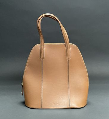 a tan handbag sitting on top of a gray surface
