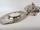 silver plated teapot and saucer on a tray on a white surface