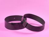 une paire de bracelets en cuir noir sur fond rose