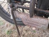a rusted motorcycle wheel with a chain attached to it