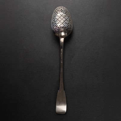 a silver spoon with a metal handle on a black surface