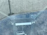 a clear table with a glass top sitting on a sidewalk