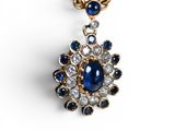 un gros plan d'un pendentif en forme de diamant bleu et blanc monté sur une chaîne en or