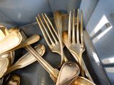 a lot of silver spoons and forks in a blue bowl