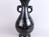 a black vase that is sitting on a white surface