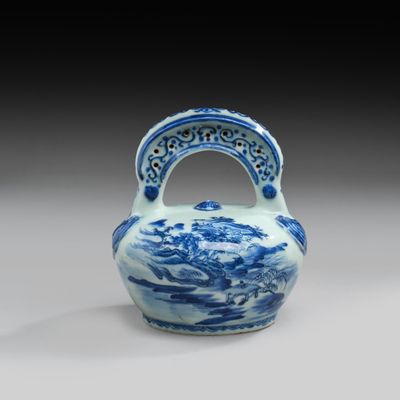 blue and white vase with a handle on a gray surface