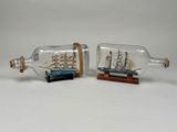 two miniature ships in a bottle with a wooden base