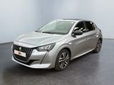 Une voiture argentée est garée dans une pièce au sol noir.