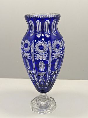 un vase bleu posé sur une table avec un mur blanc en arrière-plan