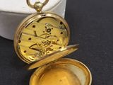une image représentant une montre de poche en or posée sur une boîte blanche
