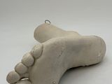 a clay sculpture of a foot on a white surface