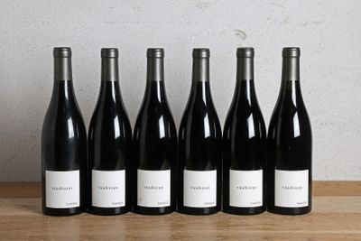 six bouteilles de vin sont alignées sur une table en bois