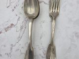 deux cuillères en argent et une fourchette posées sur une table en marbre