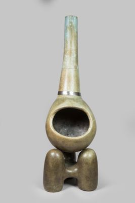 un petit vase en bronze à long col, posé sur un socle