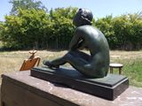 une statue en bronze représentant une femme assise sur une boîte