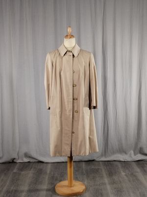 une photo d'un manteau posé sur un mannequin devant un rideau