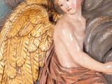 a statue of an angel sitting on top of a cloud