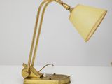 a gold desk lamp with a white shade on top of it