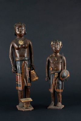 two wooden statues of a man and a woman standing next to each other