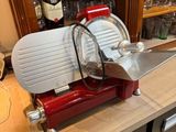 a red and silver meat slicer sitting on a counter