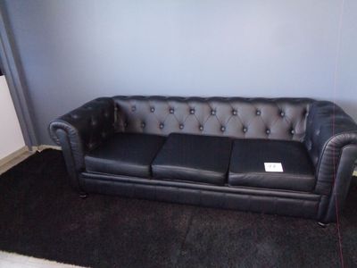 un canapé en cuir noir dans un salon avec un tapis noir