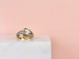 un gros plan d'une bague en or et diamants posée sur un bloc de marbre