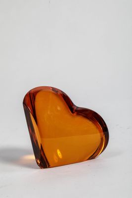 un objet en verre en forme de cœur posé sur une surface blanche