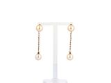 une paire de boucles d'oreilles en perles et en or, présentée sur un présentoir