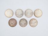 six different coins are arranged in a row on a white surface