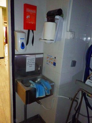 un lavabo dans une salle de bains avec un distributeur de serviettes fixé au mur