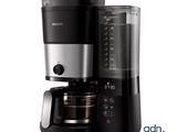 La cafetière est noire et argentée et dispose d'une carafe en verre.