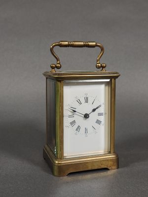 une petite horloge en laiton avec des chiffres romains sur le cadran
