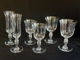 six verres à pied en verre transparent sont alignés sur une table noire