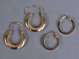 three pairs of gold hoop earrings on a gray surface