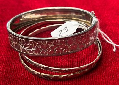 trois bracelets en argent sur un tissu rouge avec une étiquette de prix