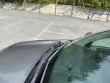 a black car parked in a parking lot with trees in the background