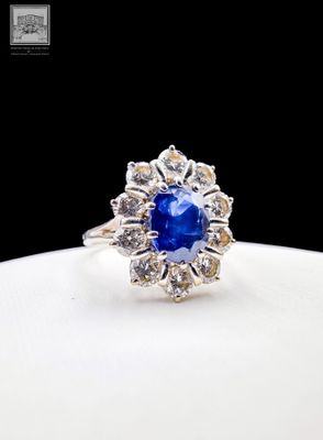 a close up of a blue sapphire and diamond ring on a white plate