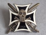 une broche argentée et noire sur laquelle figurent un crâne et des épées