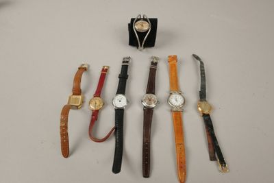 plusieurs montres différentes et un présentoir à montres posés sur une table