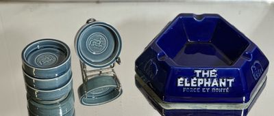 un cendrier en verre bleu et quatre tasses bleues posés sur une table
