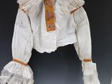 a white shirt with orange trim and ruffles hanging on a wall