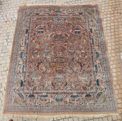 un tapis persan ancien posé sur un sol en briques, avec une personne debout à côté