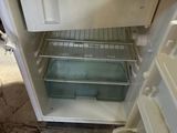 a small white refrigerator with its door open on the floor