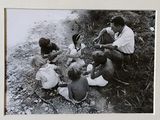 photographie en noir et blanc représentant un groupe de personnes assises au bord d'une rivière