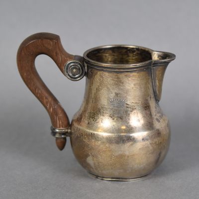 a silver pitcher with a wooden handle on a table