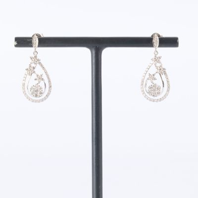 a pair of diamond earrings on a stand on a white background