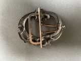 a close up of a metal brooch with a pin on it