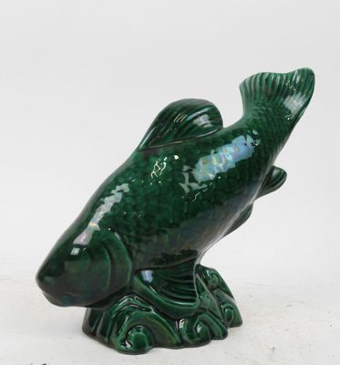 a green fish figurine sitting on top of a table
