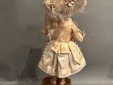 an antique doll with a hat and dress on top of a box