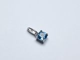 une image représentant un pendentif composé d'une topaze bleue et de diamants, posé sur une surface blanche